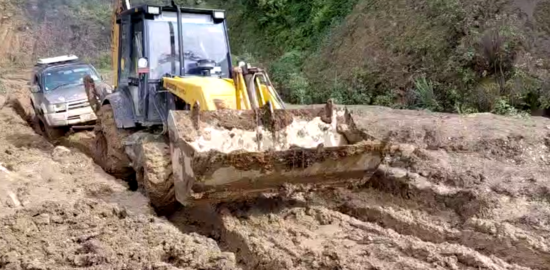 Road conditions in Chin State with the photo showing an SUV car being pulled along the muddy road.